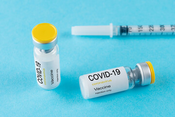 Coronavirus vaccine vial glass with a syringe on blue background. Covid-19 medicine vaccination concept. World pandemic concept.