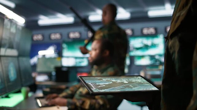 Army operative using tablet in command center housing operational missile defense system designed to intercept ballistic rockets. Close up of expert using tracking software on device, camera B