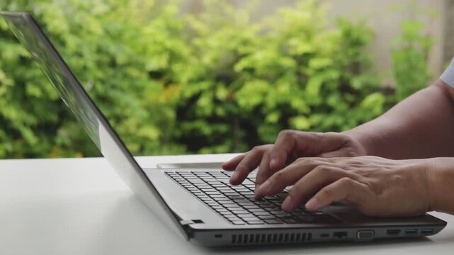 Close up of freelancer's developer hands typing program code on laptop keyboard in coworking. Businessman at work in working in cafe. Copywriter writing text on computer keyboard in coffee shop.