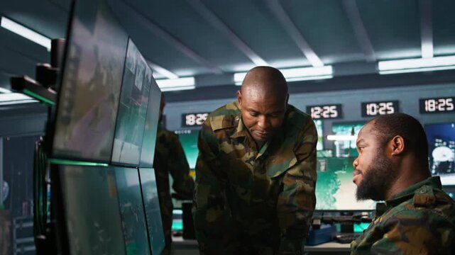 Team of soldiers looking at screens in command center housing operational missile defense system designed to intercept ballistic rockets. Tracking equipment operators using radar systems, camera B