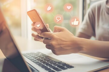 Close up of hands using social media on mobile phone and laptop computer with thumbs-up.