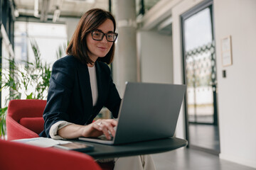 A businesswoman is deeply focused as she works on her laptop in a modern office environment