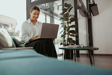 A Professional Woman is Actively Engaged in Working on Her Laptop in a Modern Office Space