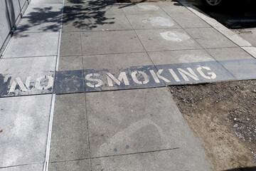 Weathered faded NO SMOKING sign painted on sidewalk