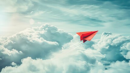 A red paper airplane flies through a cloudy sky with a bright, sunlit background.