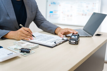 Asian business professional in a formal suit works at a desk, reviewing financial charts. manage...