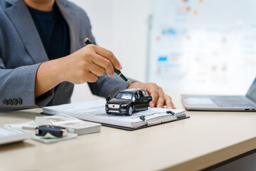 Asian business professional in a formal suit works at a desk, reviewing financial charts. manage car insurance claims, analyze auto loan options, sign lease agreements for vehicle transactions.