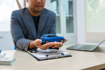 Asian business professional in a formal suit works at a desk, reviewing financial charts. manage car insurance claims, analyze auto loan options, sign lease agreements for vehicle transactions.