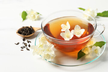Hot jasmine tea in cup and flowers on white marble table