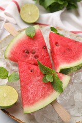 Pieces of tasty watermelon, ice cubes, lime and mint on table, closeup