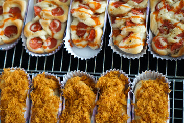 Chicken floss bun and sausage swirl roll on cooling rack. Ready to eat. Close up.