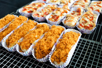Chicken floss bun and sausage swirl roll on cooling rack. Ready to eat. Close up.