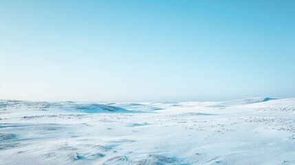 A vast, white, snow-covered landscape stretches out under a clear blue sky, punctuated by the faint trails of distant planes.
