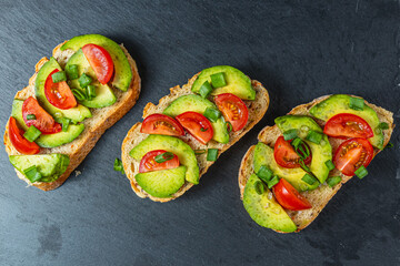 Avocado toast topped with tomato and green onion on a slice of carrot bread