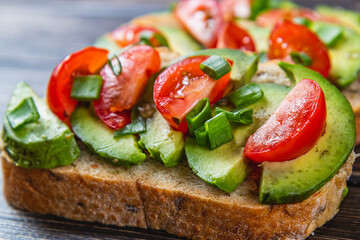 Avocado toast topped with tomato and green onion on a slice of carrot bread
