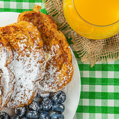 French toast on a white plate with blueberries and orange juice for breakfast