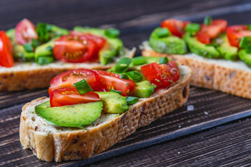 Avocado toast topped with tomato and green onion on a slice of carrot bread