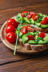 Avocado toast topped with tomato and green onion on a slice of carrot bread