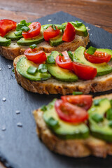 Avocado toast topped with tomato and green onion on a slice of carrot bread