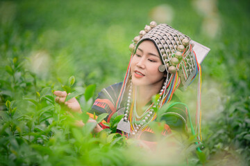 woman standing in a lush tea plantation, delicately picking tea leaves. She is dressed in traditional, vibrant clothing with intricate patterns indicating a cultural or ethnic background