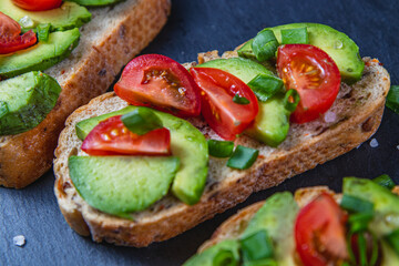 Avocado toast topped with tomato and green onion on a slice of carrot bread
