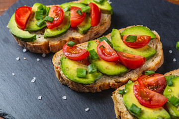 Avocado toast topped with tomato and green onion on a slice of carrot bread