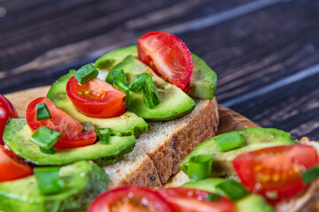 Avocado toast topped with tomato and green onion on a slice of carrot bread