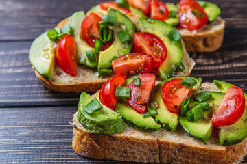 Avocado toast topped with tomato and green onion on a slice of carrot bread