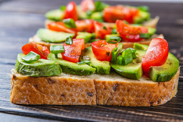 Avocado toast topped with tomato and green onion on a slice of carrot bread