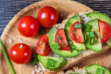 Avocado toast topped with tomato and green onion on a slice of carrot bread