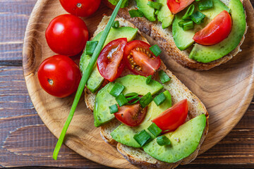 Avocado toast topped with tomato and green onion on a slice of carrot bread
