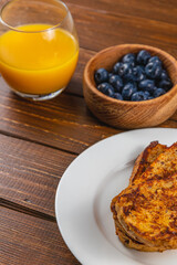 French toast on a white plate with blueberries and orange juice for breakfast