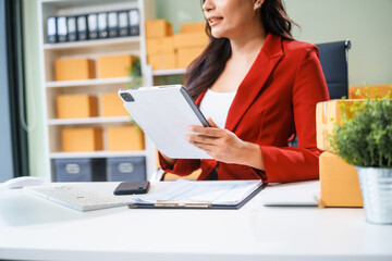 A beautiful businesswoman sits at the table, looking at the computer screen and talking on the phone. She analyzes marketing plans with a smile, feeling happy and successful in her online business.