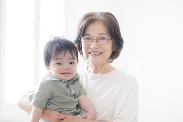 孫を抱くシニア女性のカメラ目線　おばあちゃんのイメージ