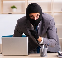 Male gangster stealing information from the office