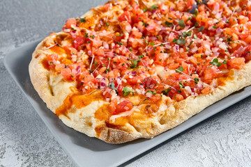 Delicious Roman Pizza with Tuna Tartare and Tomatoes on a Grey Plate
