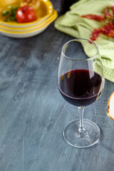 Close-Up of Red Wine Glass on Rustic Dark Table with Plates and Green Cloth in Background