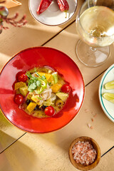 Fresh Fish Ceviche with Olives, Orange, Avocado, and Tomatoes on a Wooden Table