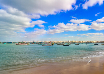 Fototapeta premium Fishing boats on the Mediterranean sea coast of Alexandria with the skyline of the city in the background on a bright sunny day at Alexandria,Egypt 