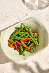 Garnish of Green Beans with Paprika in Ceramic Bowl on Light Background