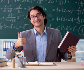 Young handsome math teacher in classroom