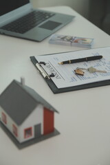 Real estate agent home sales broker is using a pen pointing to the house model and explains the business contract, rent, buy, mortgage, loan, or home insurance