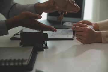 Real estate agent home sales broker is using a pen pointing to the house model and explains the business contract, rent, buy, mortgage, loan, or home insurance