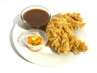 A plate of batter fried crispy chicken steak served with mixed vegetable and brown sauce isolated on white background