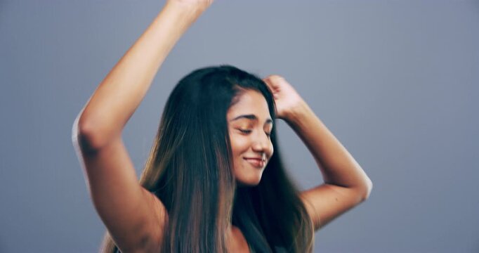 Face, dancing and Indian woman with celebration, smile and achievement on a grey studio background. Portrait, person and model with energy, excited and cheerful with hobby, success and activity