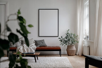 Frame mock-up on a white wall in scandinavian natural style living room, brown leather ottoman, potted plants. Empty blank vertical din A poster with black frame in light room interior design