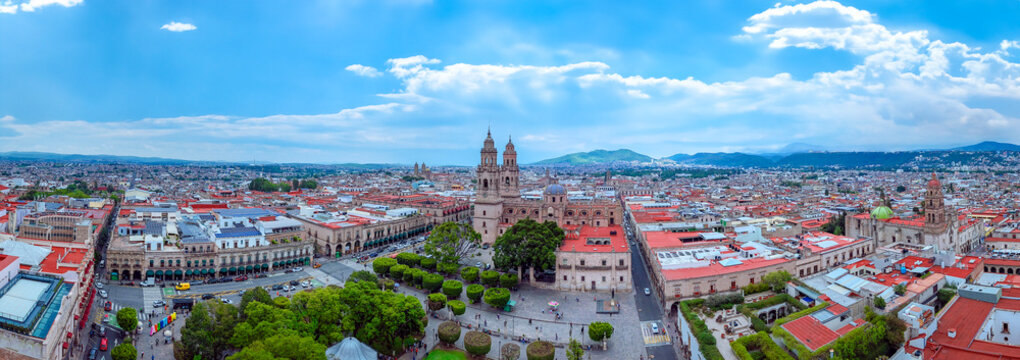 Panoramic splendor of Morelia's central plaza, Michoac&aacute;n: Majestic Baroque Novohispanic cathedral stands harmoniously amidst vibrant city life, a hub for locals and tourists alike.
