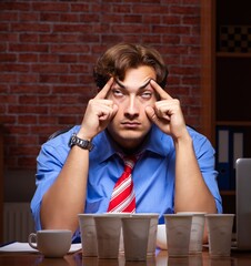 Young employee drinking coffee working at night shift