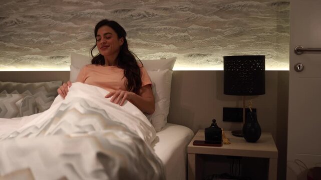 Beautiful, young woman lying down in her cozy bed and getting ready for sleeping