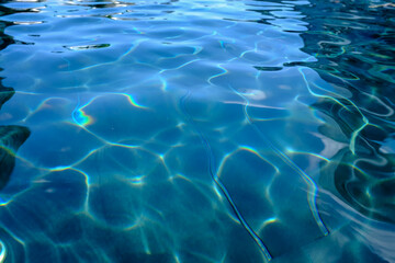 Close-up of the water of a swimming pool with the sunlight reflection. The scene of the swimming pool in the sunny day. Relaxation and holiday concept.
